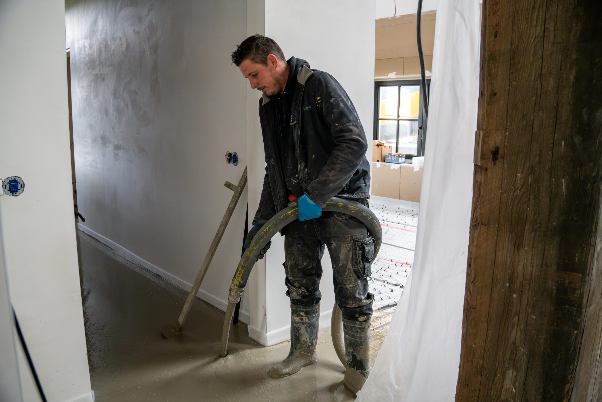 Een man stofzuigt de vloer in een opgeruimde kamer-thermo floor friesland(Oudega)