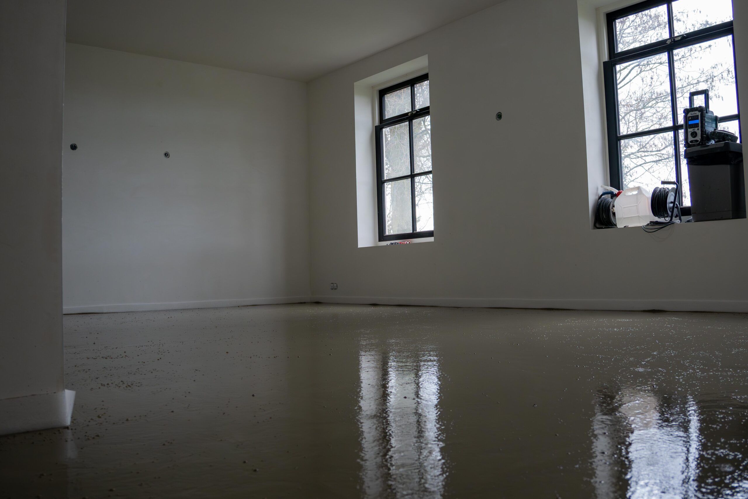 Een lege kamer met twee ramen en een kale vloer - Thermo Floor Friesland (Oudega)