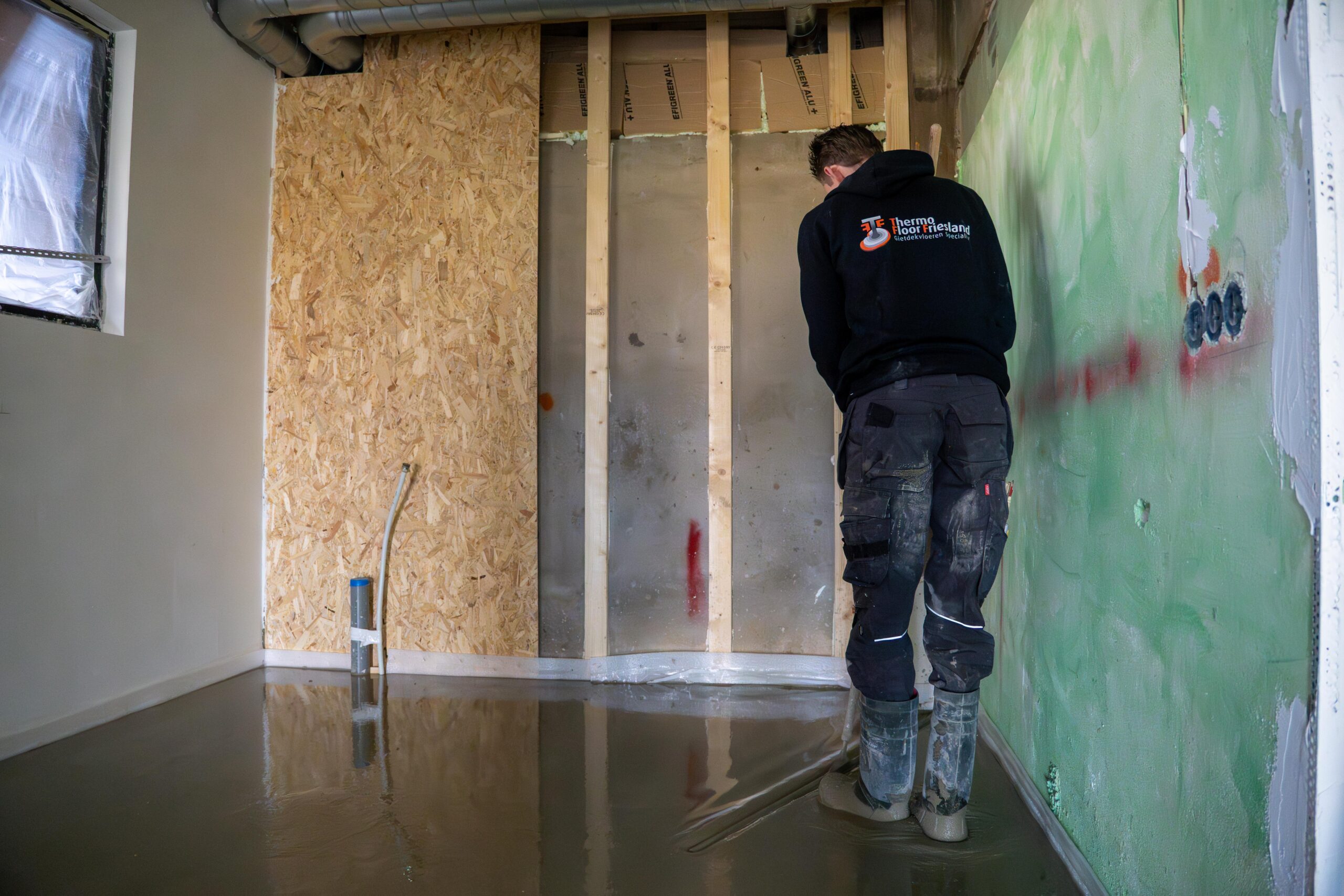 Een man staat in een kamer met een betonnen vloer-thermo floor friesland (Oudega)