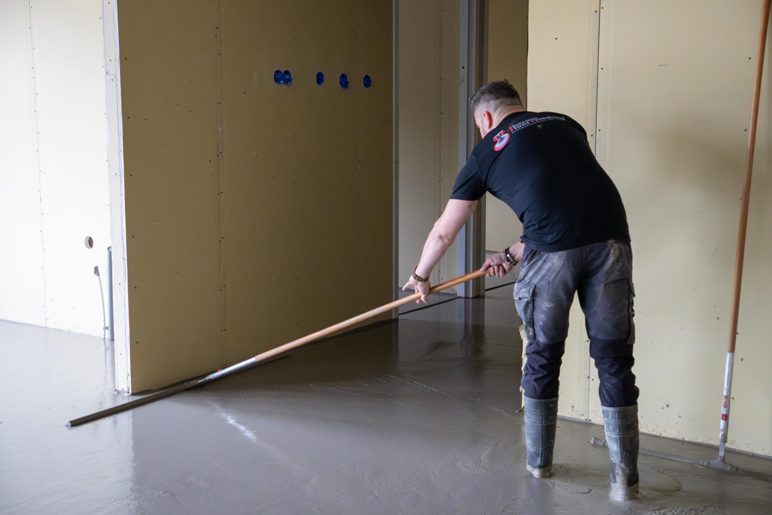 Een man veegt de vloer schoon met een bezem –Thermo Floor Friesland