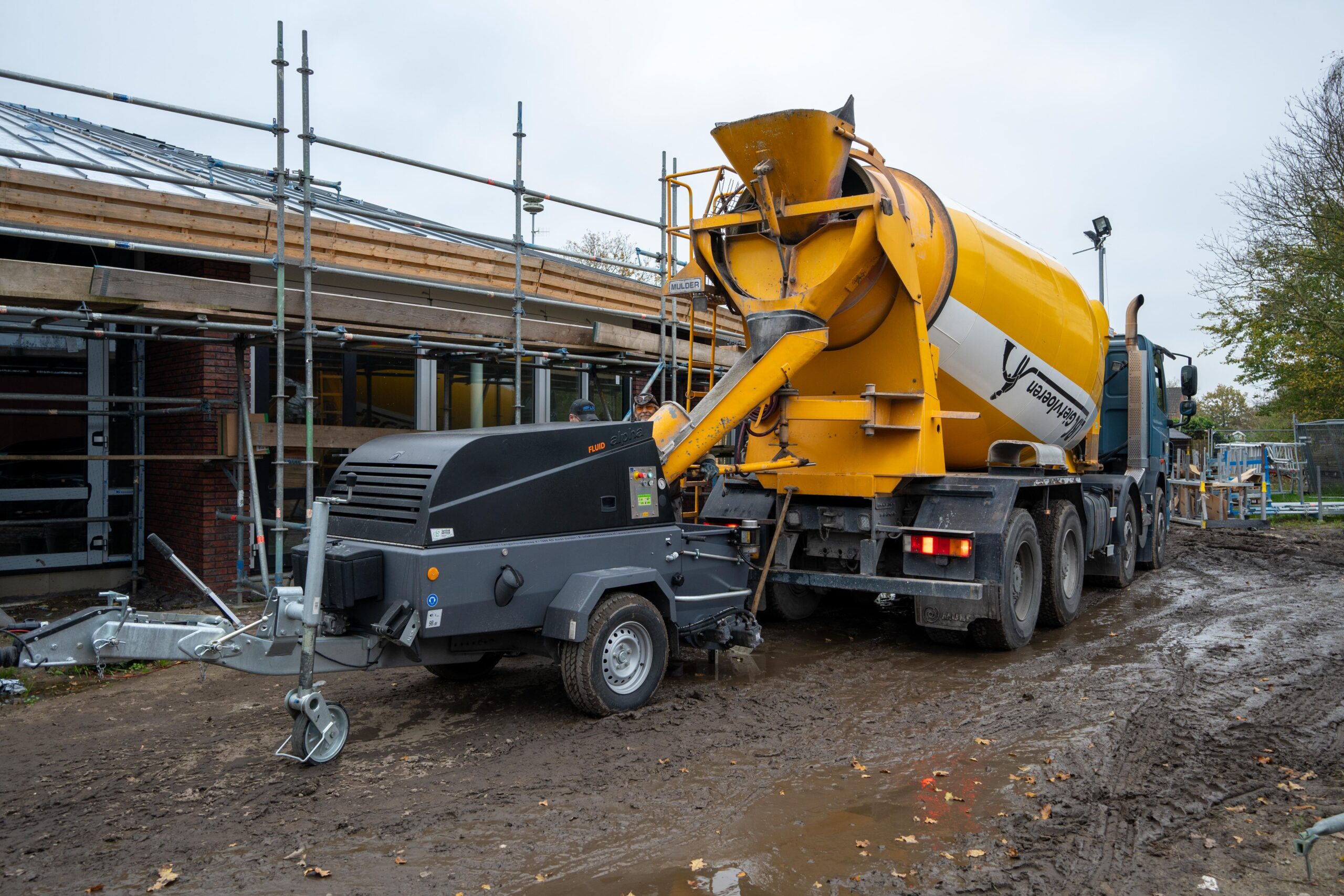 Een cementwagen geparkeerd voor een gebouw-thermo floor friesland (cementgebonden)